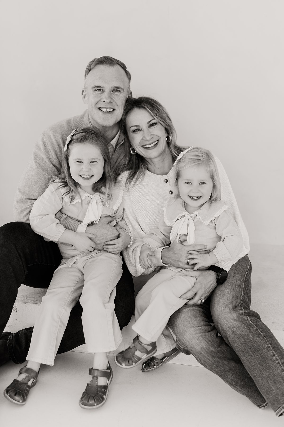 Black and white photo series showing a casual family portrait progression with joyful expressions in matching outfits.