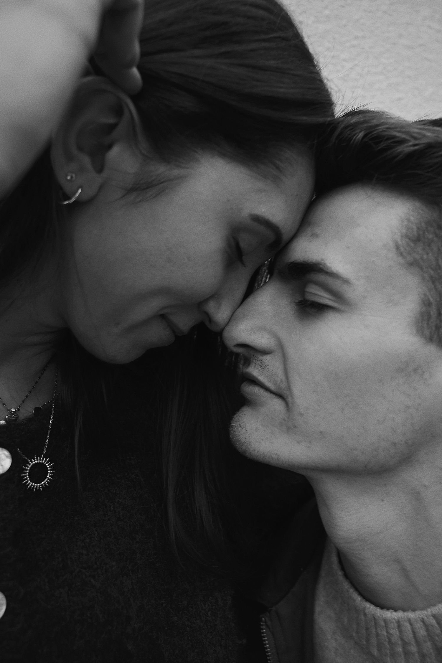 A romantic black and white close-up portrait of a couple with their faces close together in an intimate moment.