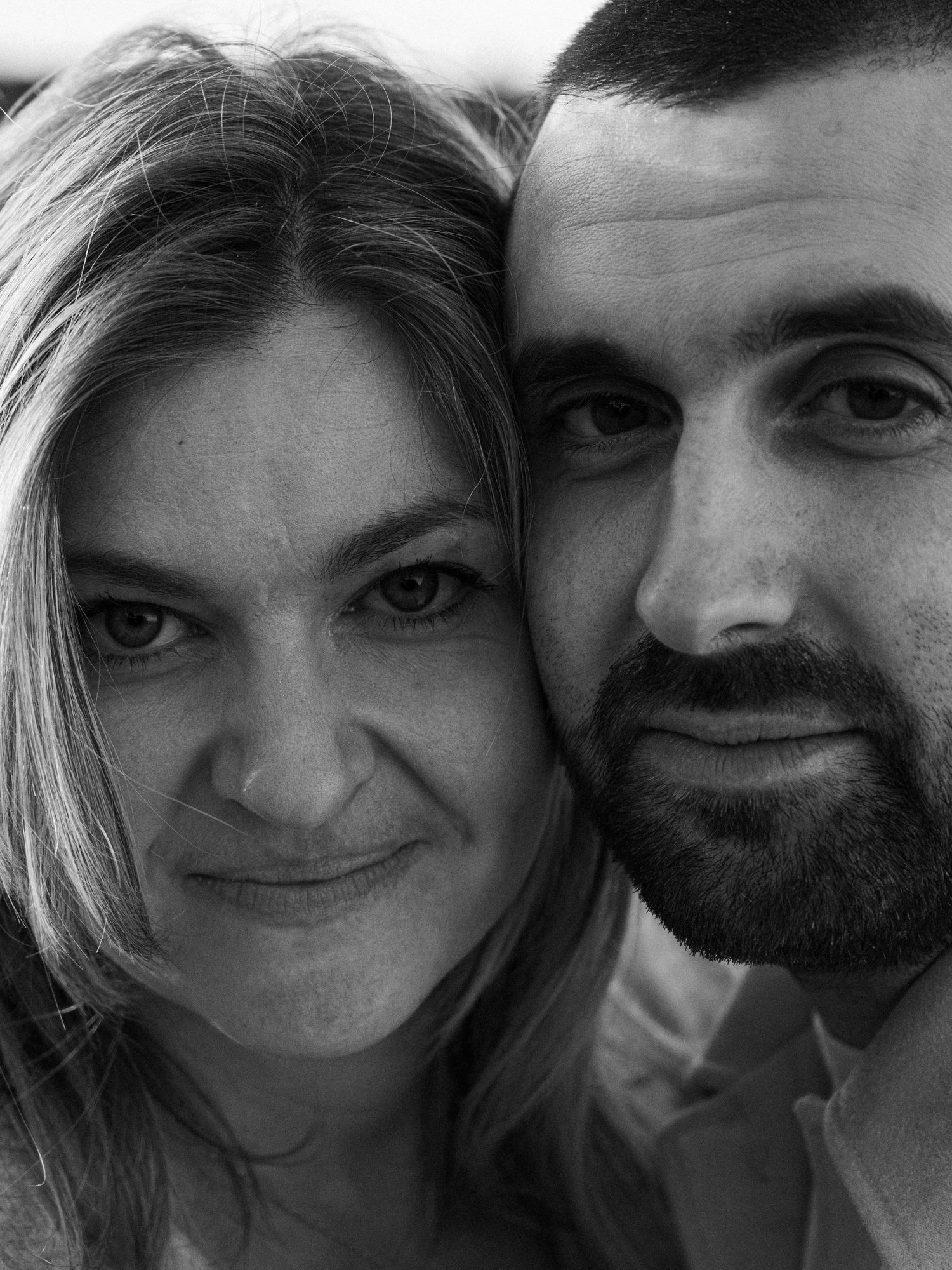 Close-up black and white portrait of a couple smiling at the camera together.