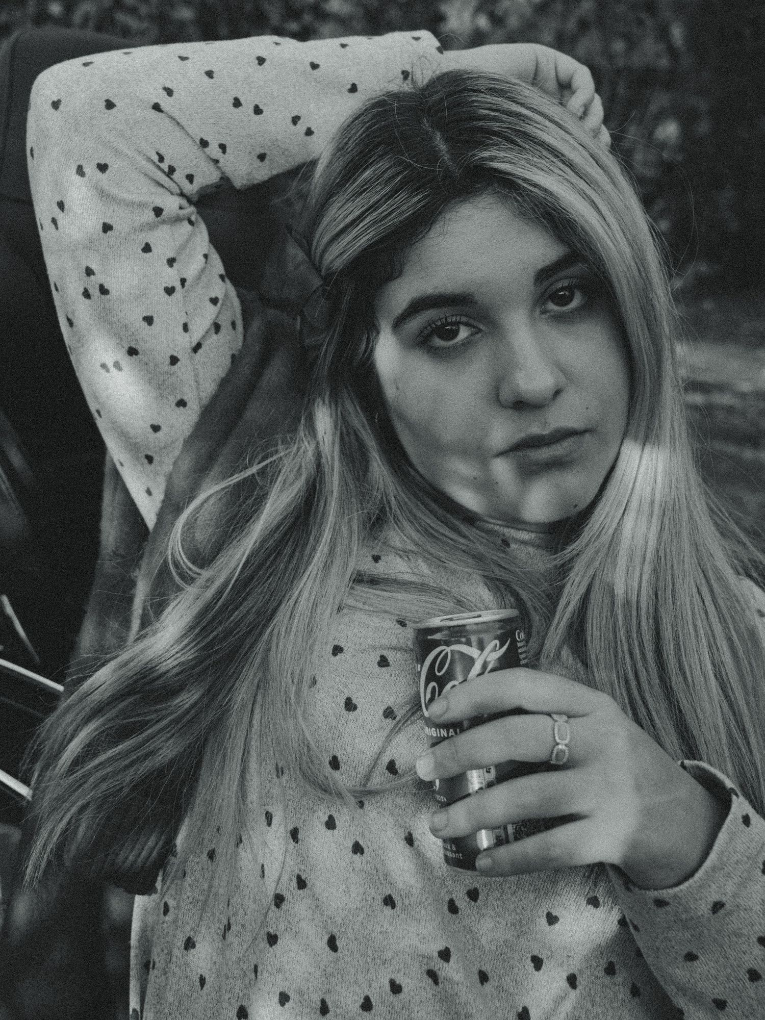 A black and white portrait photograph showing long blonde hair and a polka dot top with rings on the fingers.