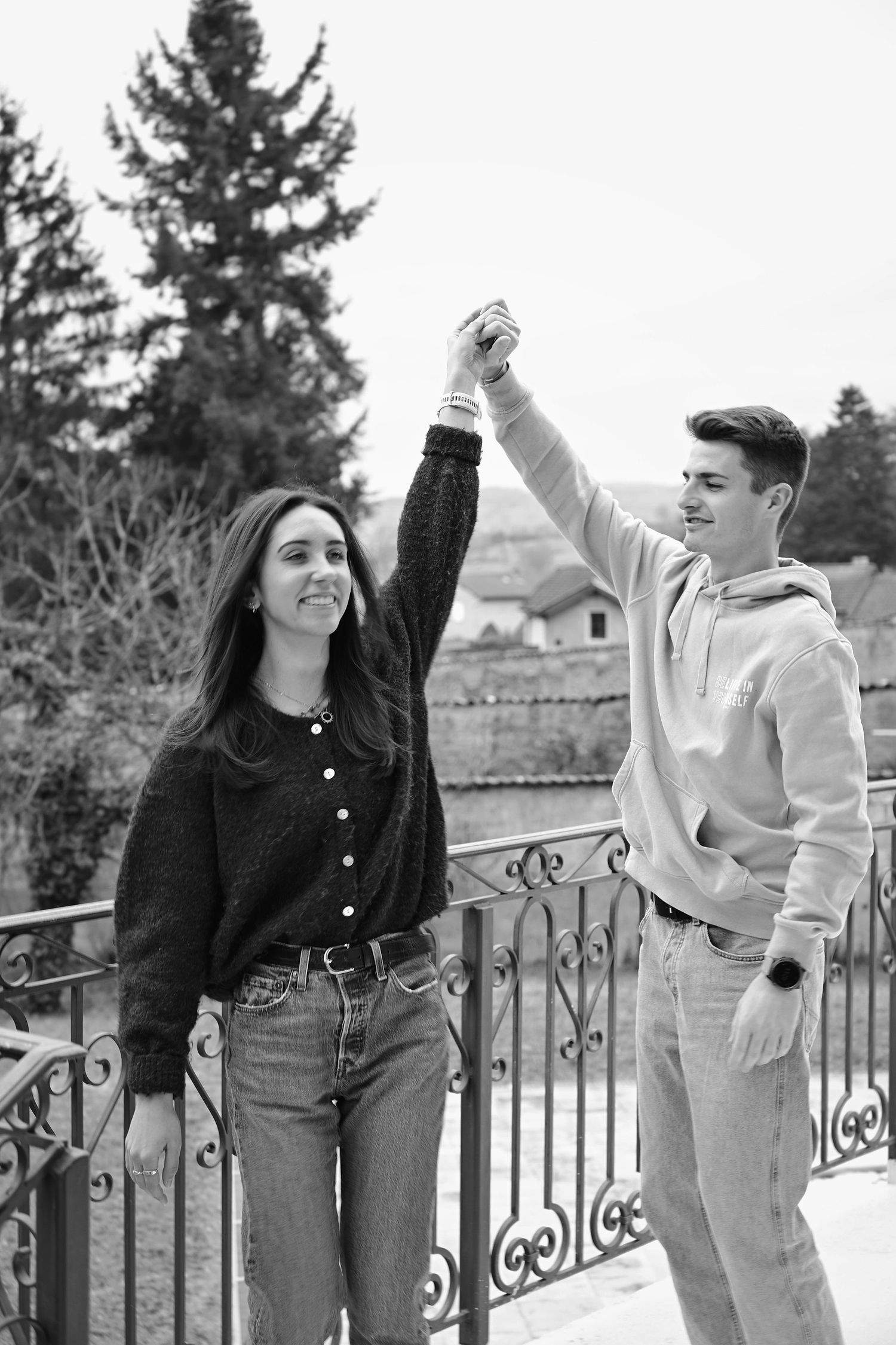 A couple dancing and holding hands on a balcony with mountain views.