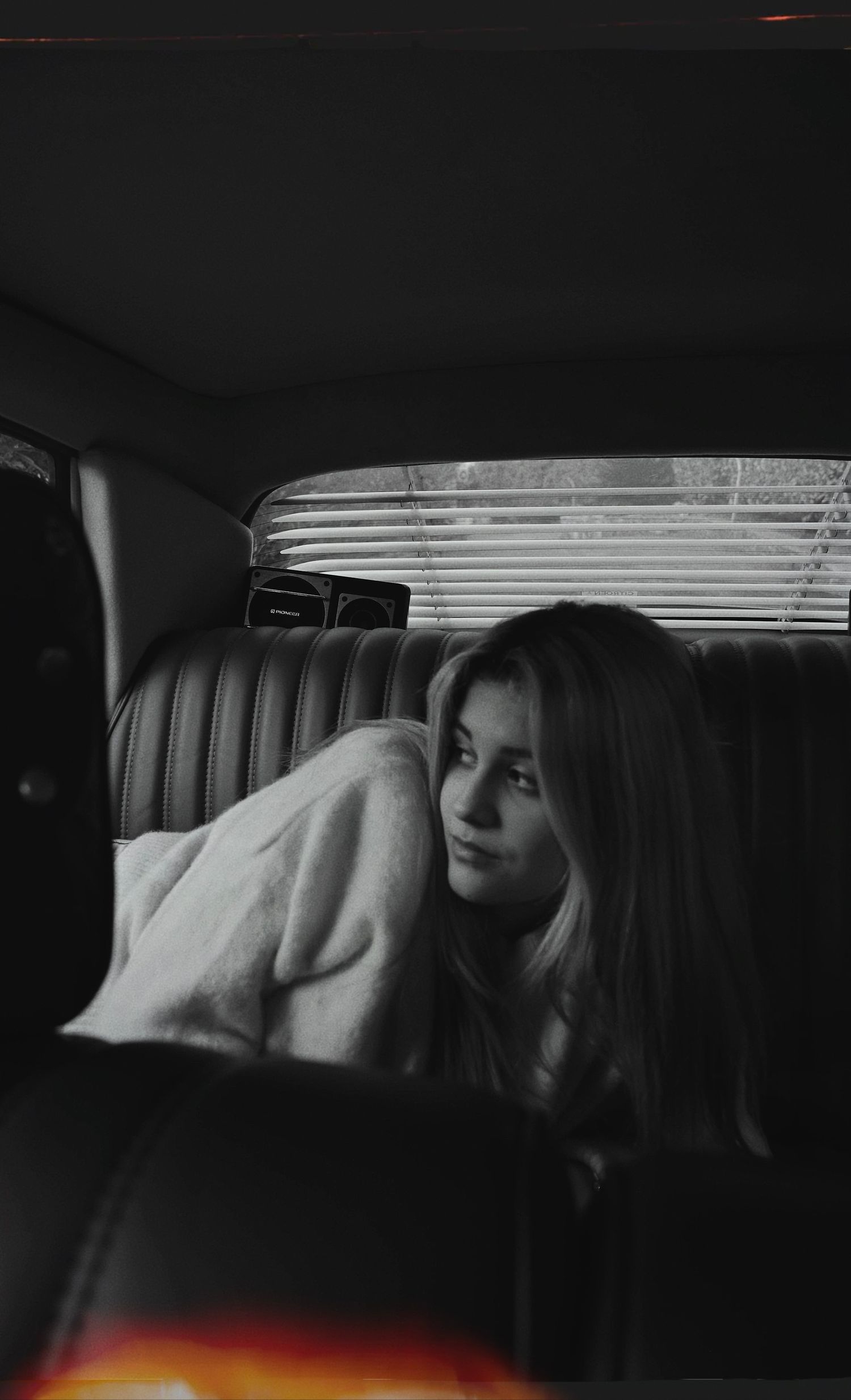 A person reclining on leather car seats in a moody black and white photograph.