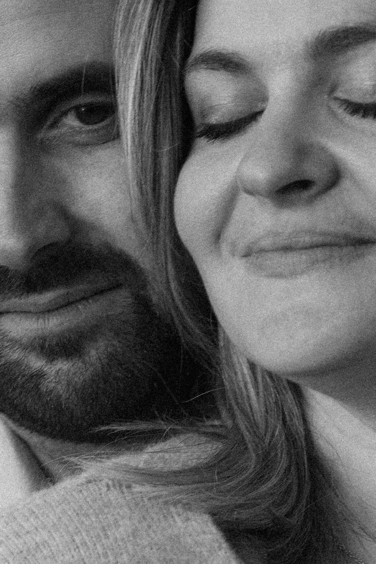 A close-up black and white portrait of a couple smiling with their eyes closed in a tender moment.