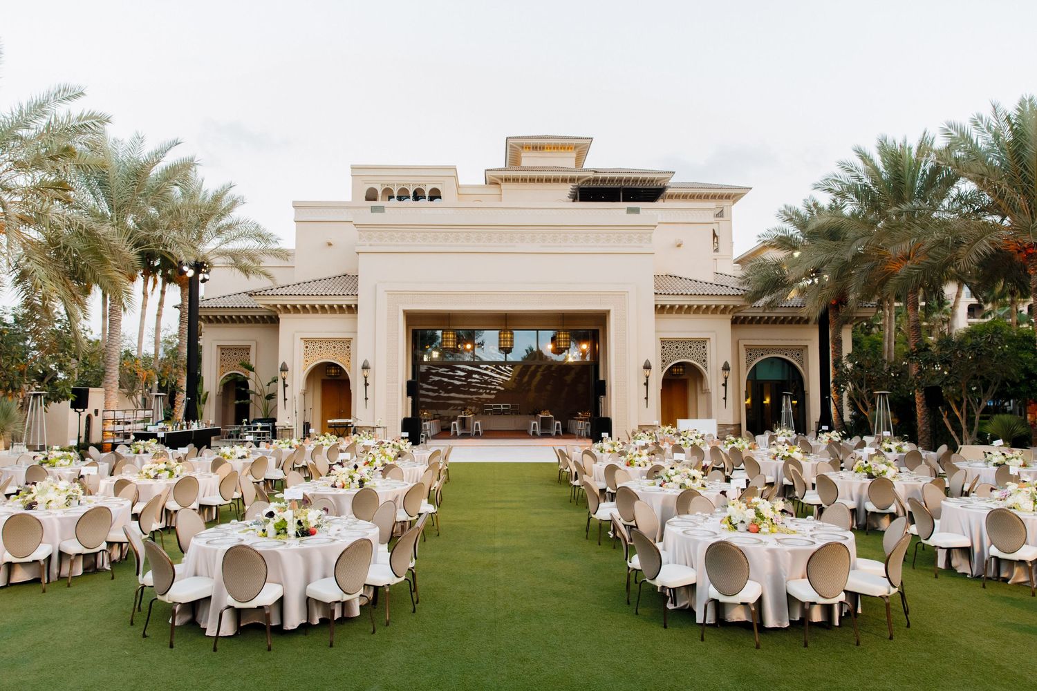 Luxurious outdoor wedding reception venue with white decor and palm trees in Dubai.