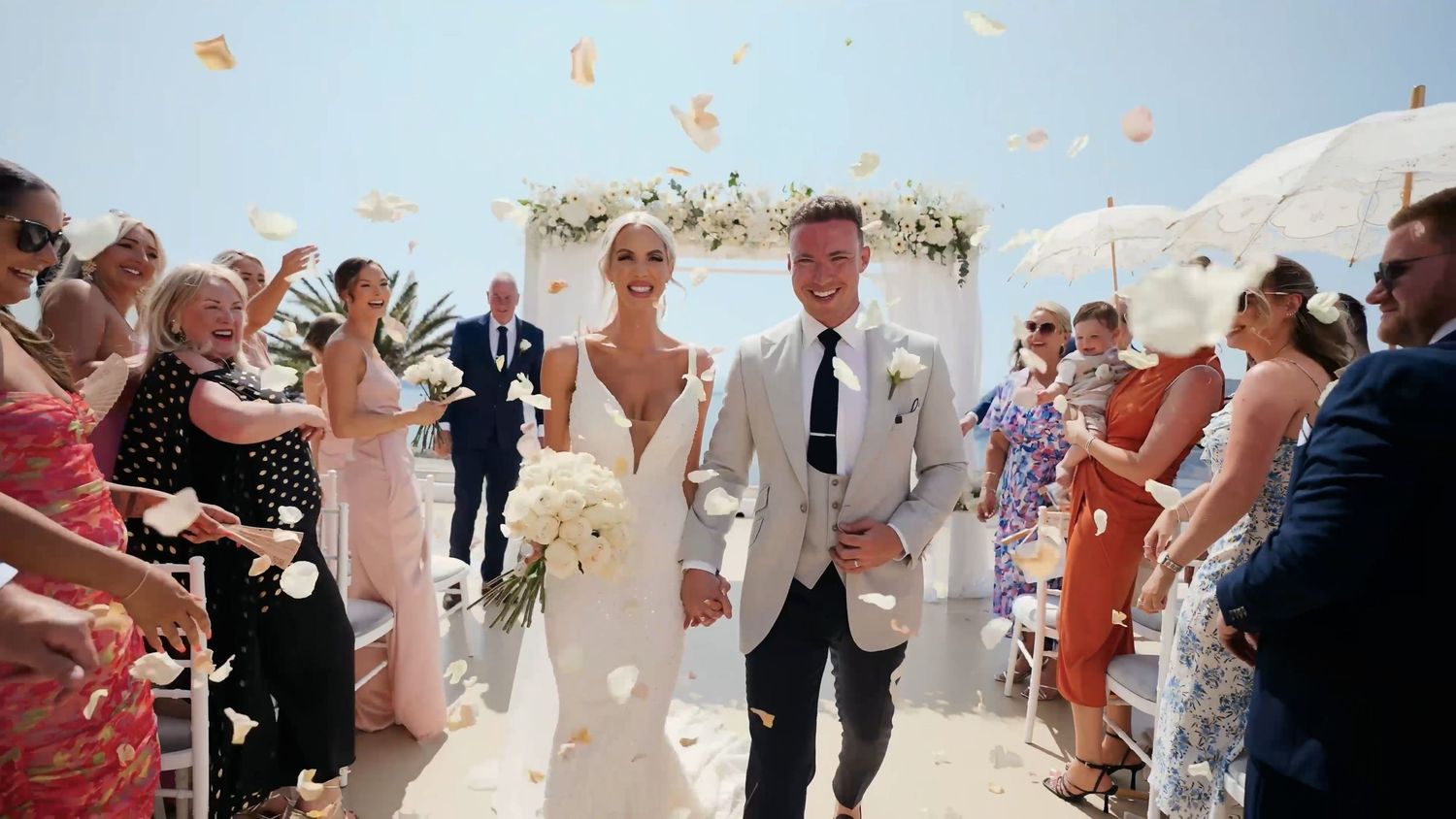 Joyful wedding celebration with flower petals being tossed in the air.