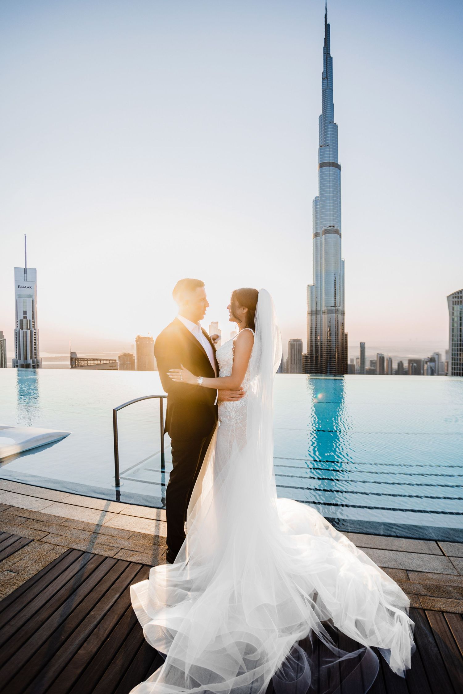 A romantic wedding photo of a couple in front of the iconic Burj Khalifa in Dubai during sunset.