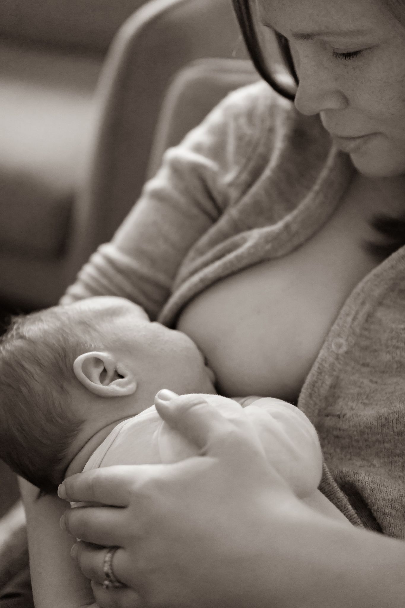 Svartvit bild på en intim stund där mamma tittar på sin bebis som ammar. Fotograf, nyföddfotograf, Umeå, Västerbotten