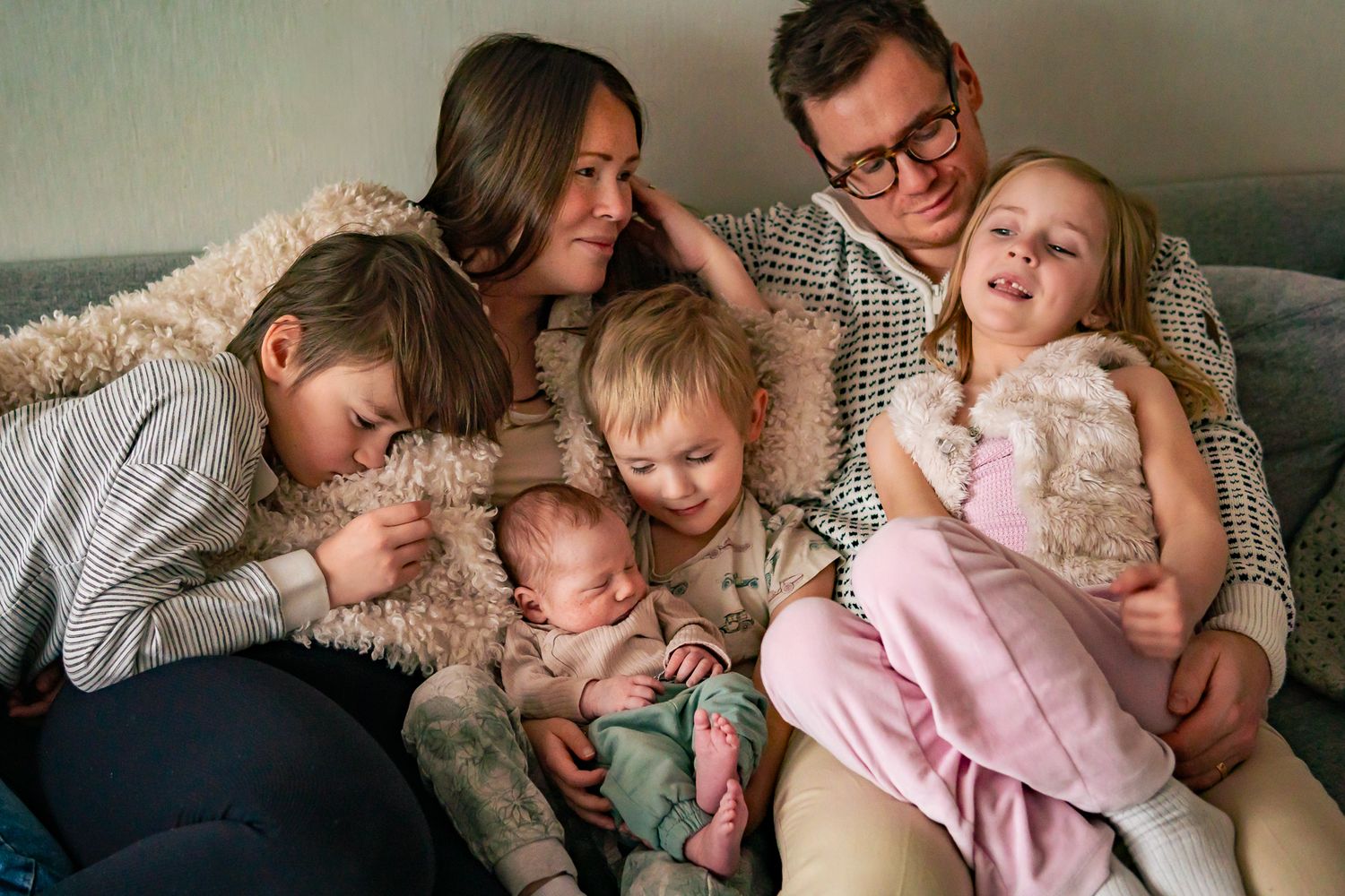 En stor familj på 6 personer har krupit ihop tillsammans i soffan för mys och skratt. Fotograf, nyföddfotograf, Umeå, Västerbotten