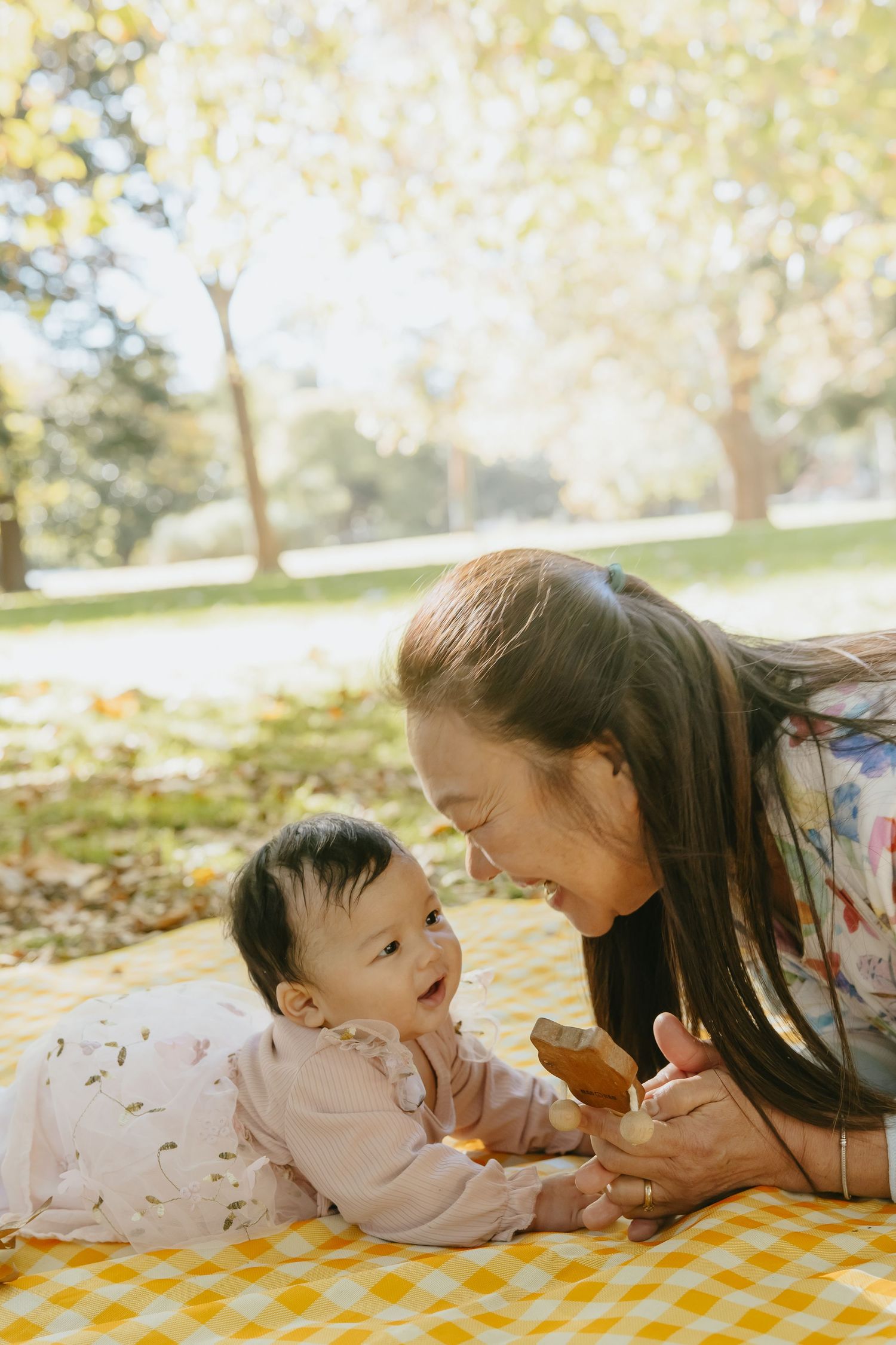 A joyful family moment on a yellow checkered blanket during an autumn picnic in a sunlit park.