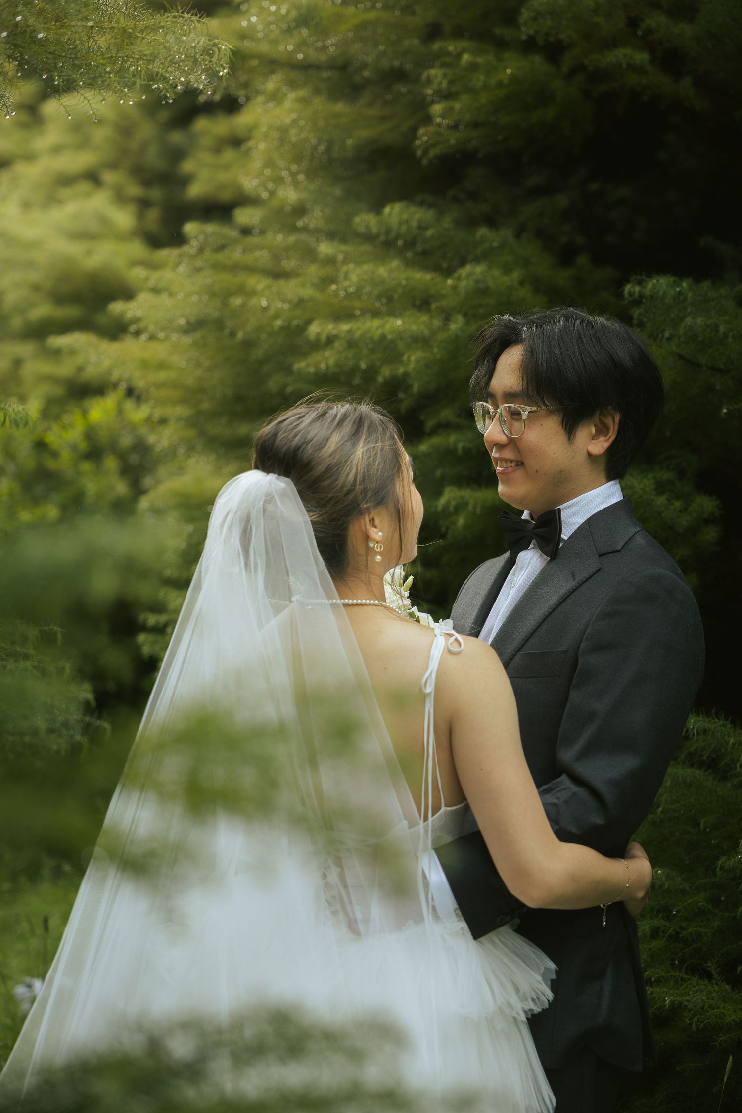A bride and groom share an intimate moment in a lush garden setting with soft natural lighting.