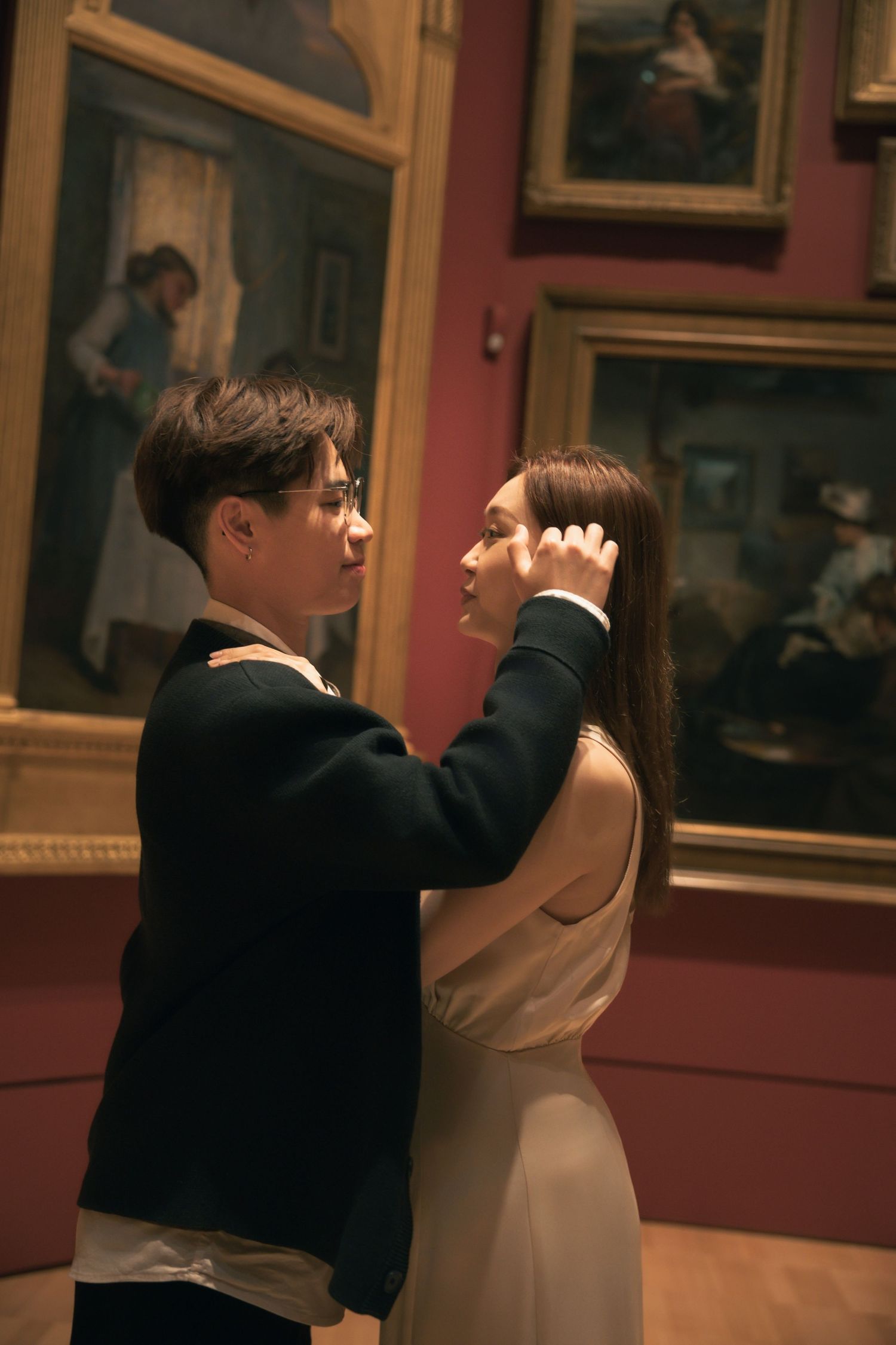 A couple dances together in a dimly lit art gallery surrounded by classical paintings.