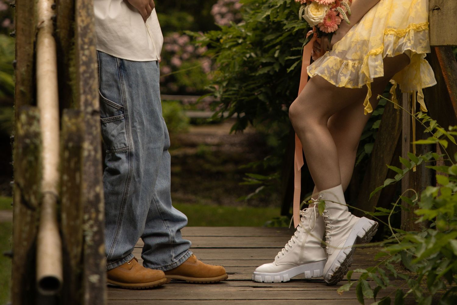 Legs of people standing in a garden wearing casual shoes and jeans.
