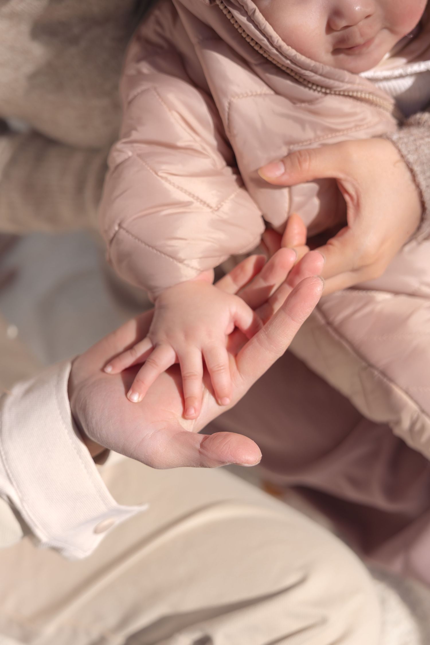 Close-up of tender hands touching together wearing soft beige clothing in gentle natural lighting.