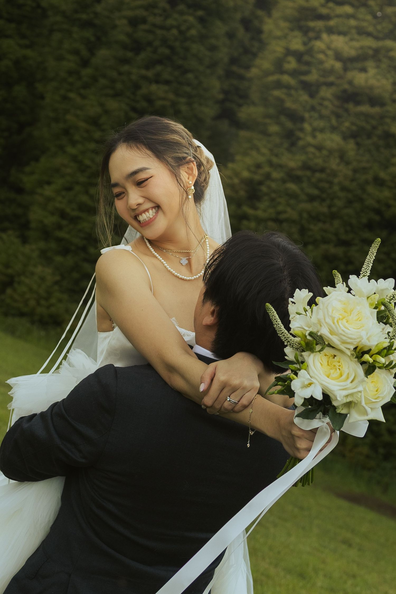 A couple in wedding attire embraces on a green lawn with white roses in a romantic sequence of photos.