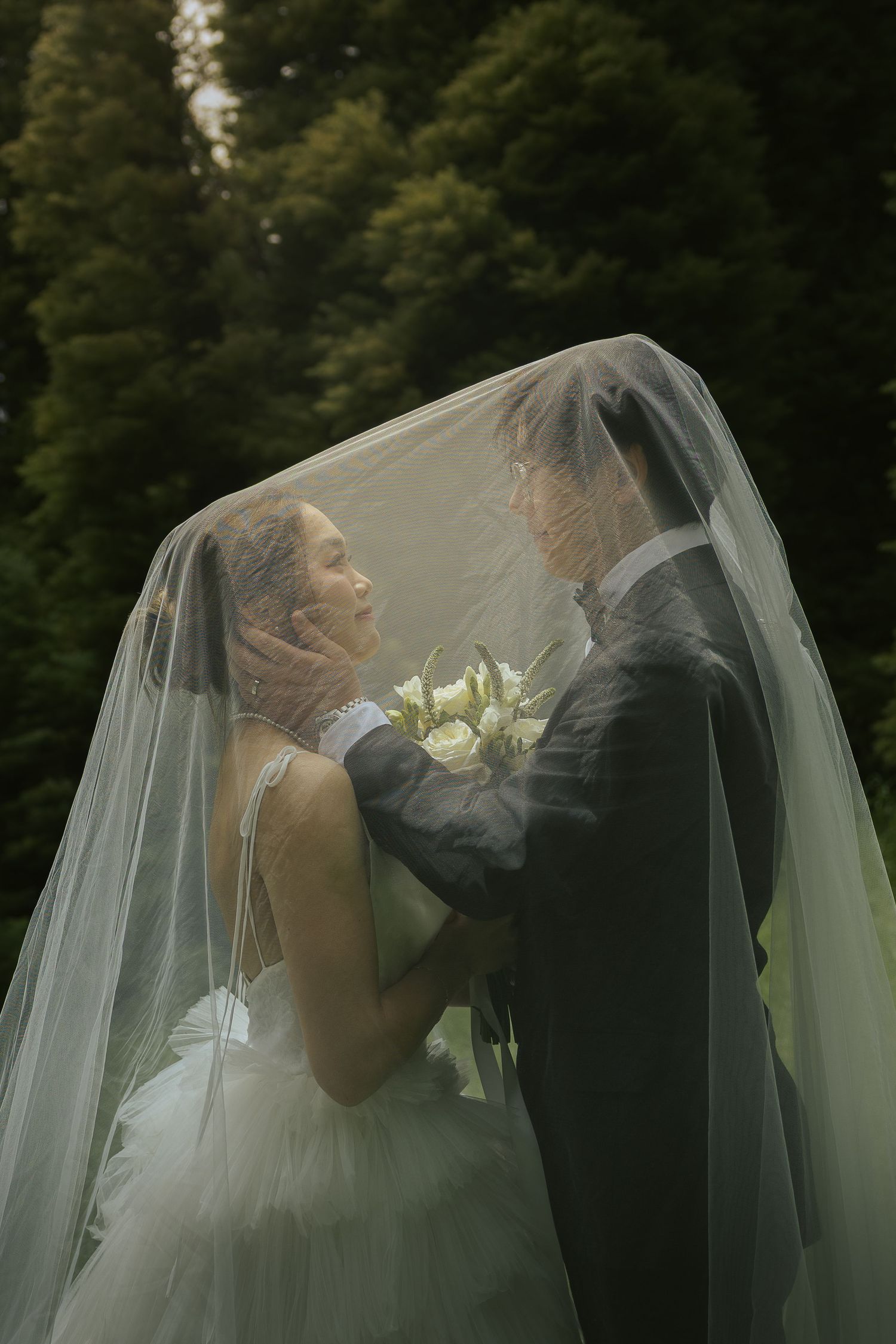 Romantic wedding sequence shows couple sharing intimate kisses under a flowing white veil in a garden setting.
