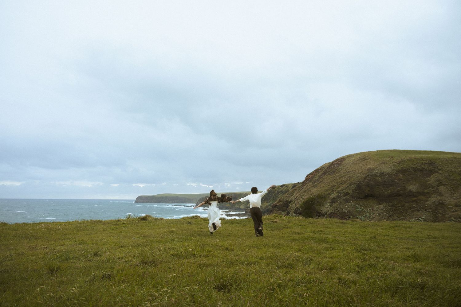 Scenic coastal landscape with rolling green hills and rugged cliffs overlooking a misty ocean view.