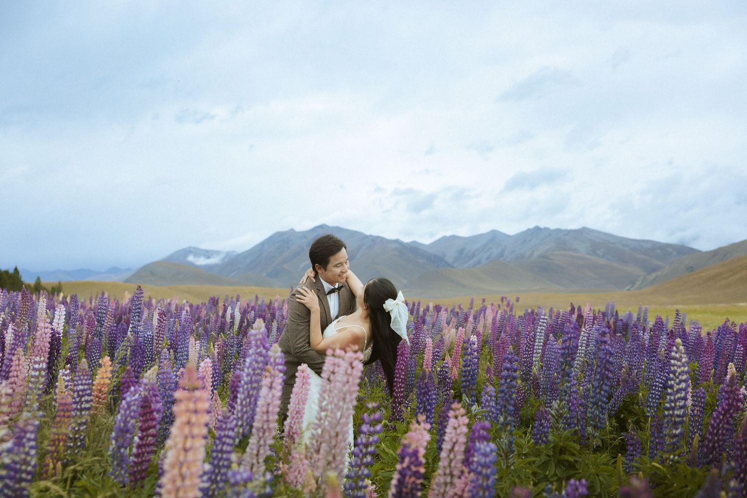 Scenic mountain landscape with vibrant purple lupine flowers blooming in a field during summer.