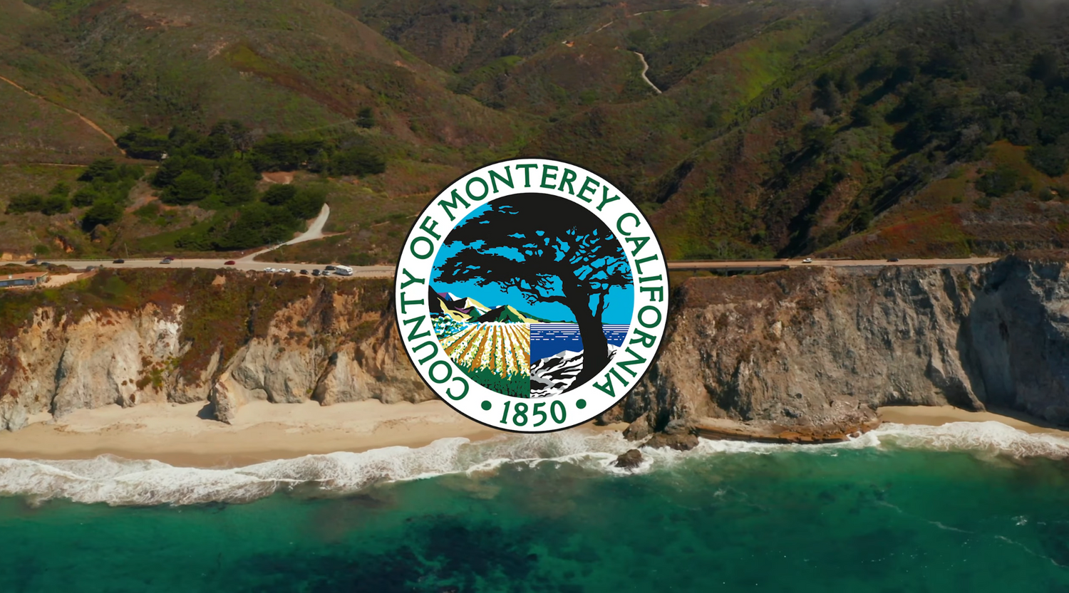 Monterey County seal overlaid on aerial view of coastal cliffs and ocean.