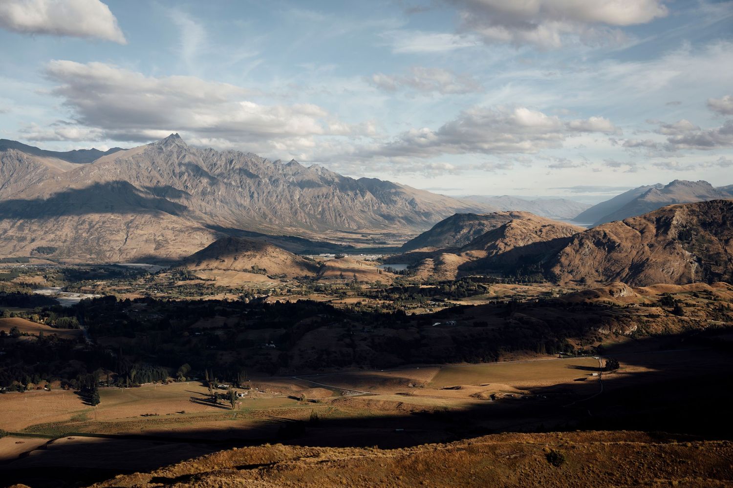 Aerial panoramic view of the Wakatipu Basin in Queenstown, with rugged peaks and golden plains in New Zealand.