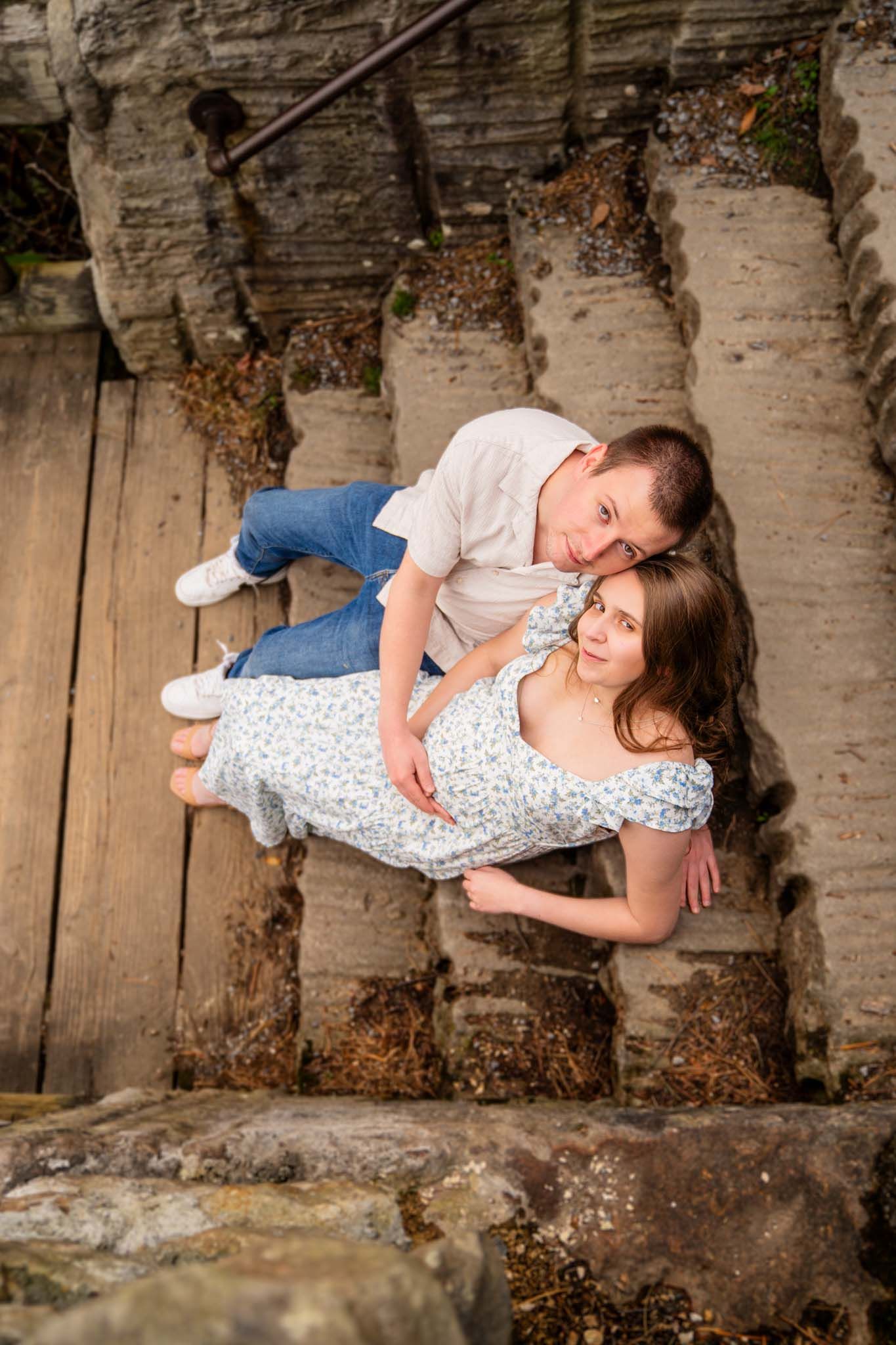 Couple sitting together on weathered stone steps outdoors, sharing a tender embrace.