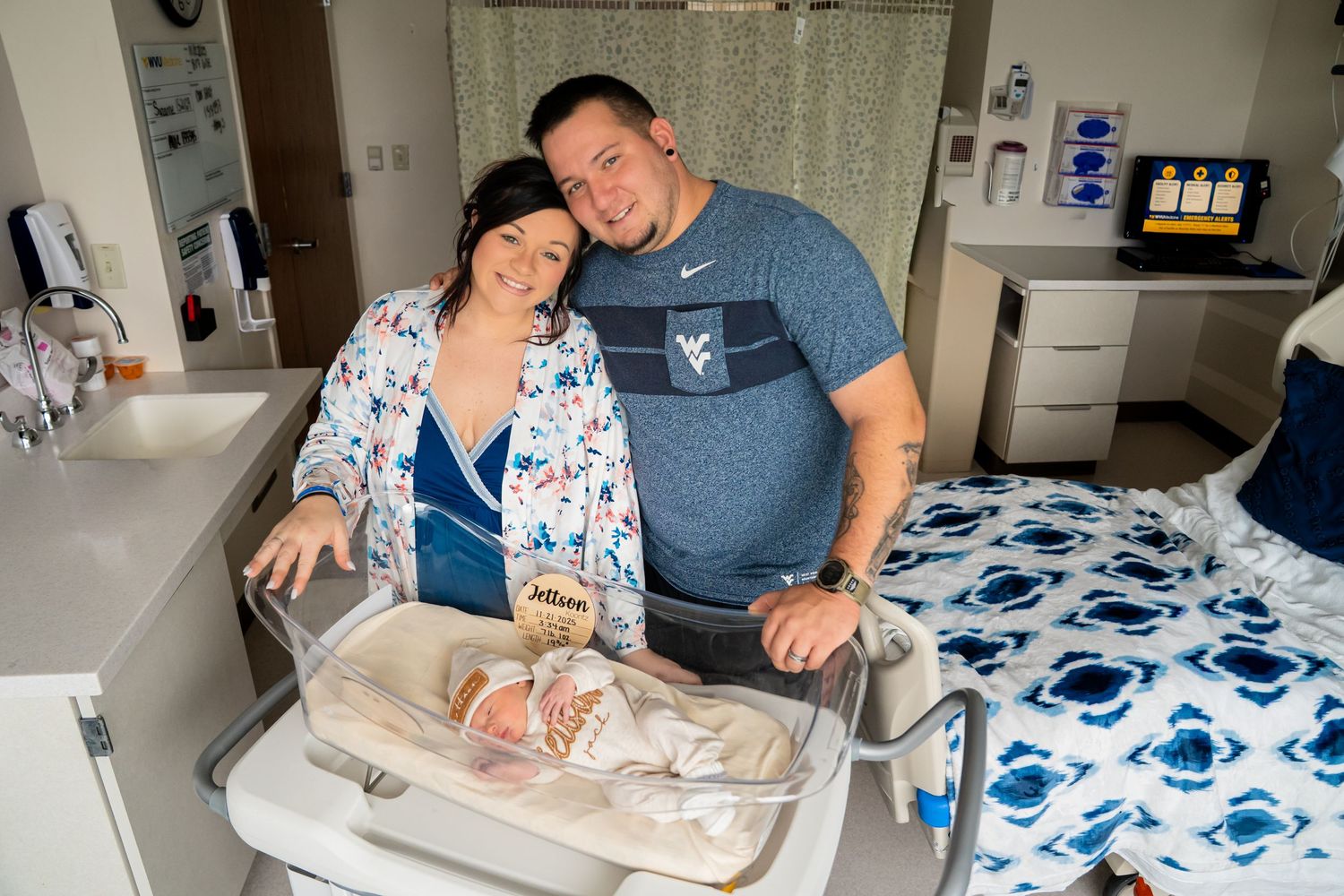 Happy couple posing with their newborn baby in a hospital room.