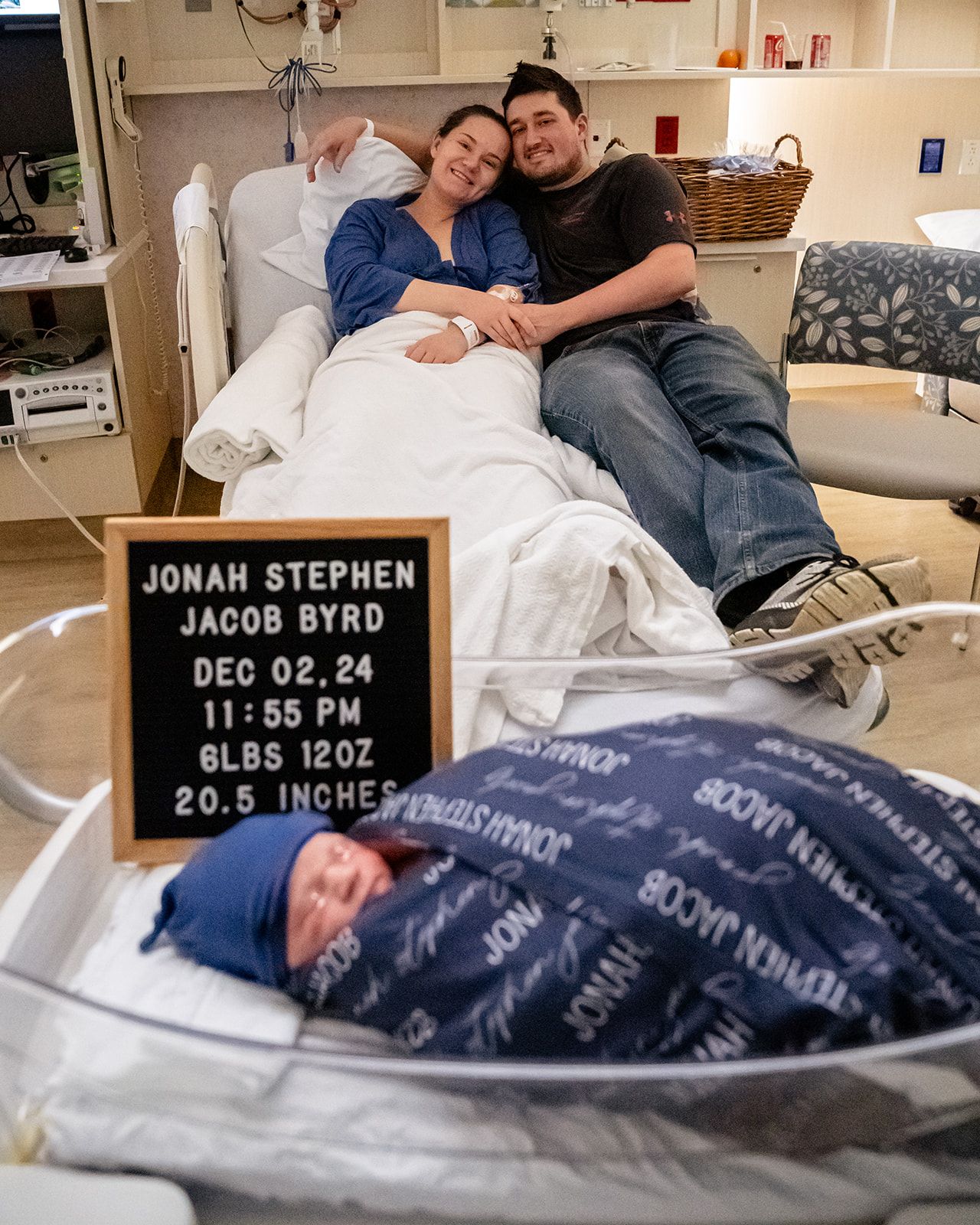 New parents posing with birth announcement sign for Jonah Stephen Jacob Byrd born Dec 02 2024.