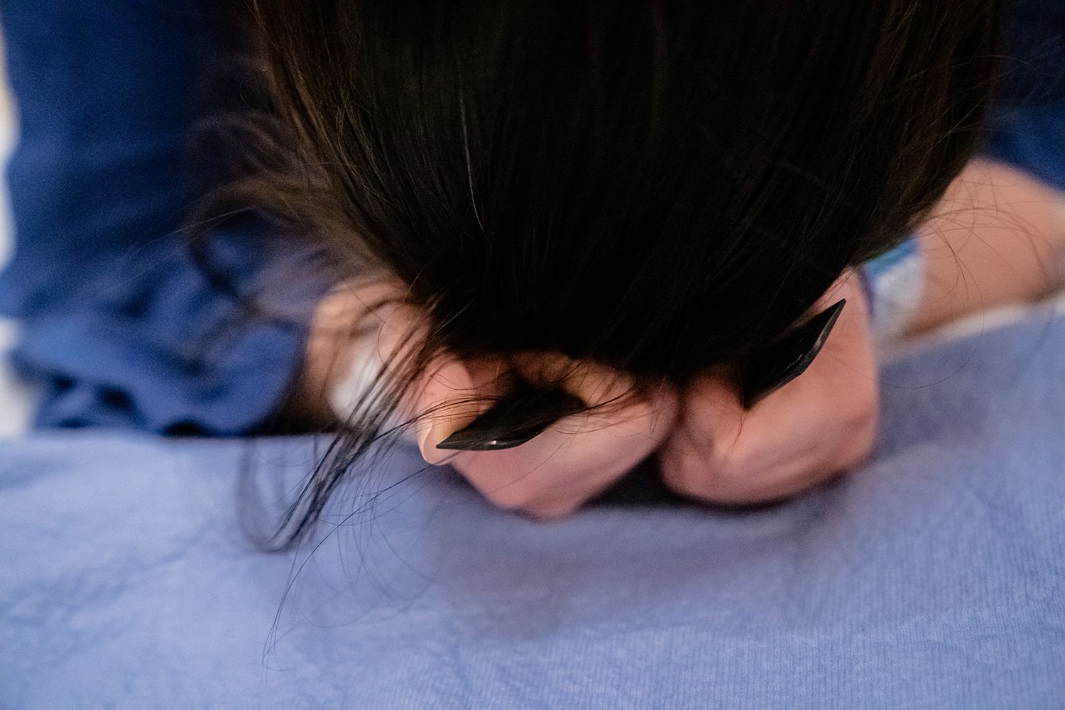 Woman in labor gripping hospital bed sheets tightly during intense contraction while giving birth.