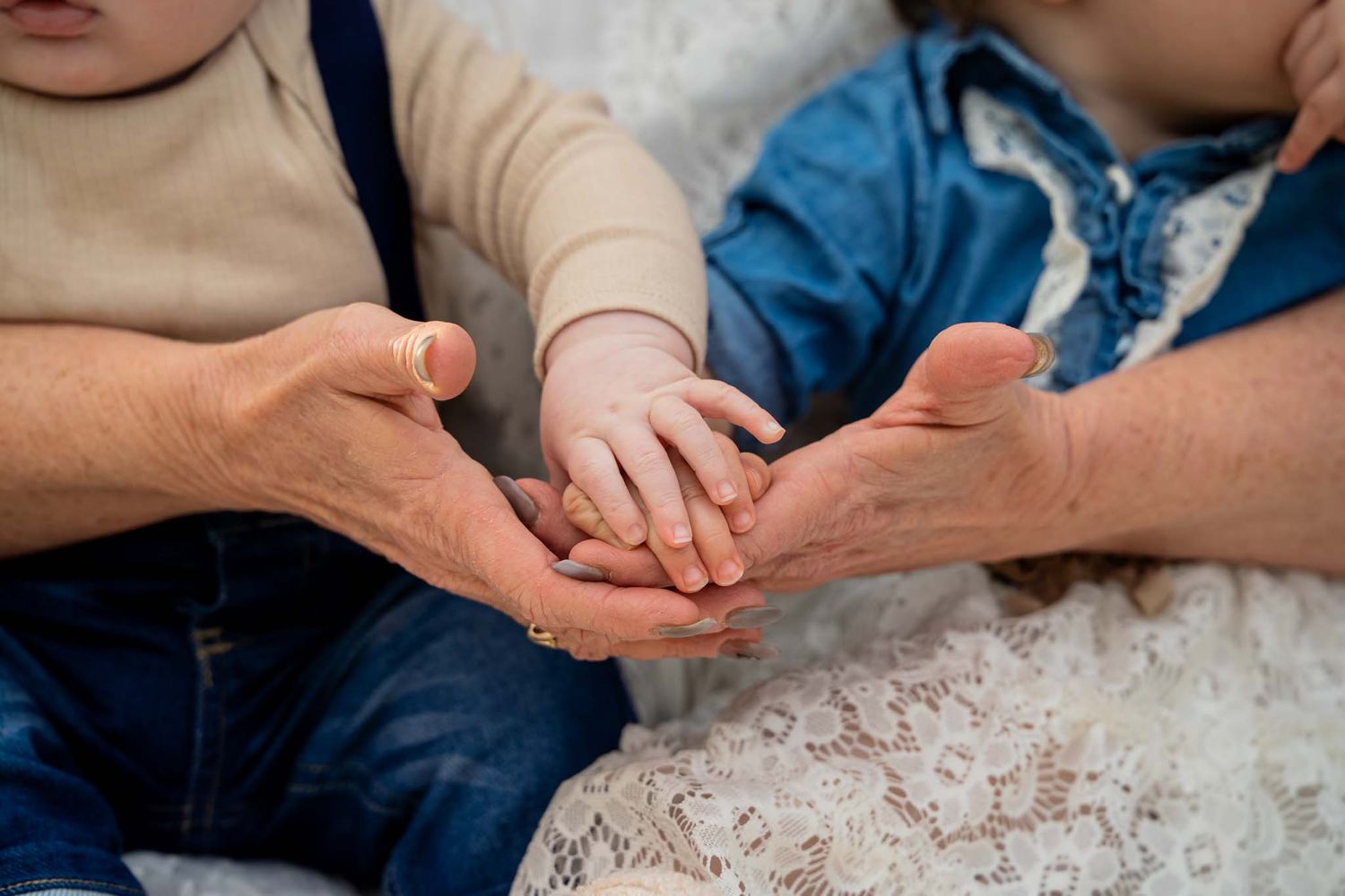 Close-up of adult and baby hands gently touching together in a tender moment.