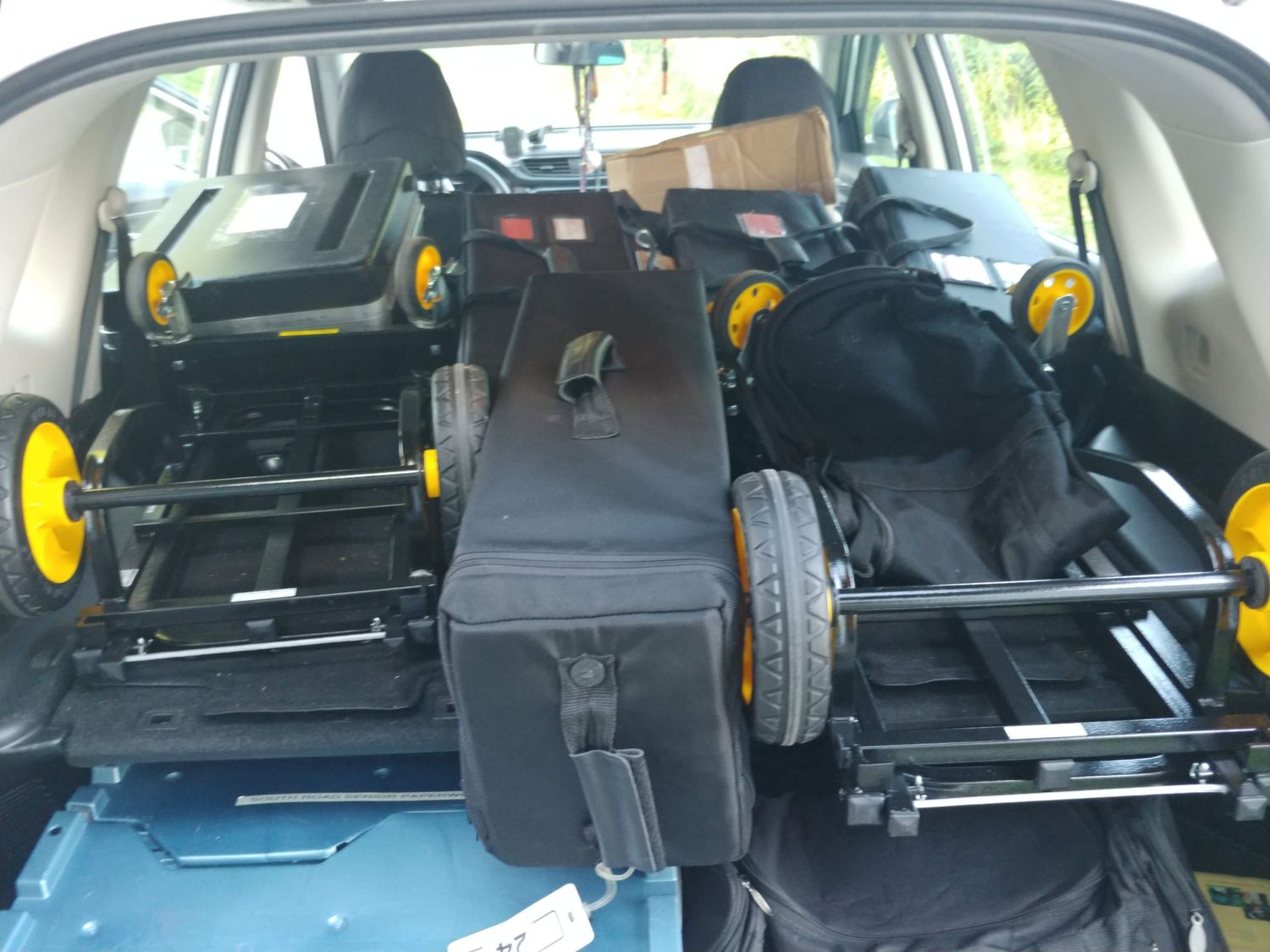 Car trunk loaded with folded wheelchairs and mobility equipment secured with yellow wheels visible.
