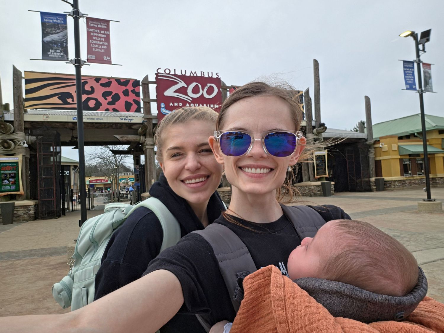 Two young women taking a selfie with a newborn baby at the Columbus Zoo entrance.