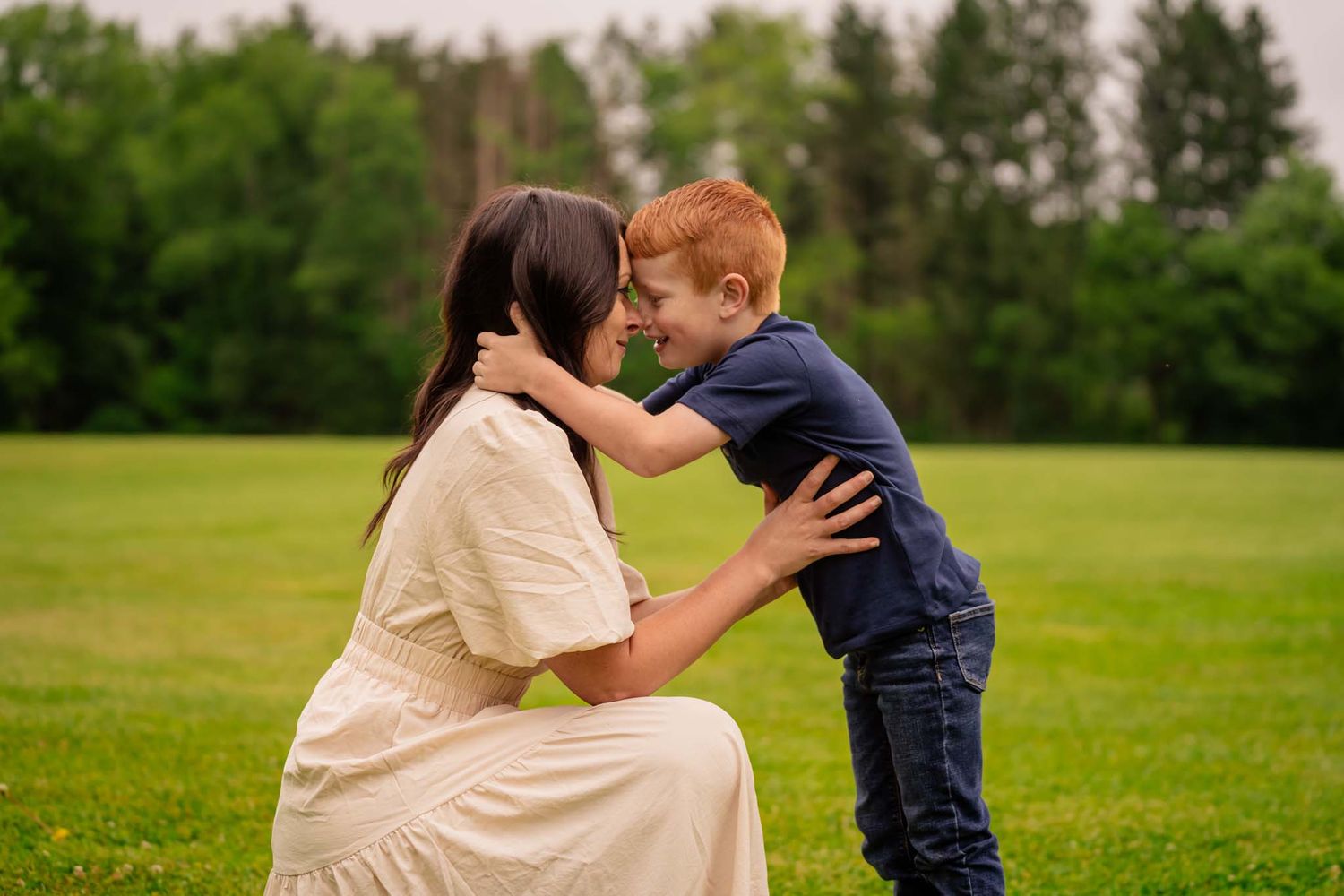Mother kneeling in grass sharing a tender moment with her young son.
