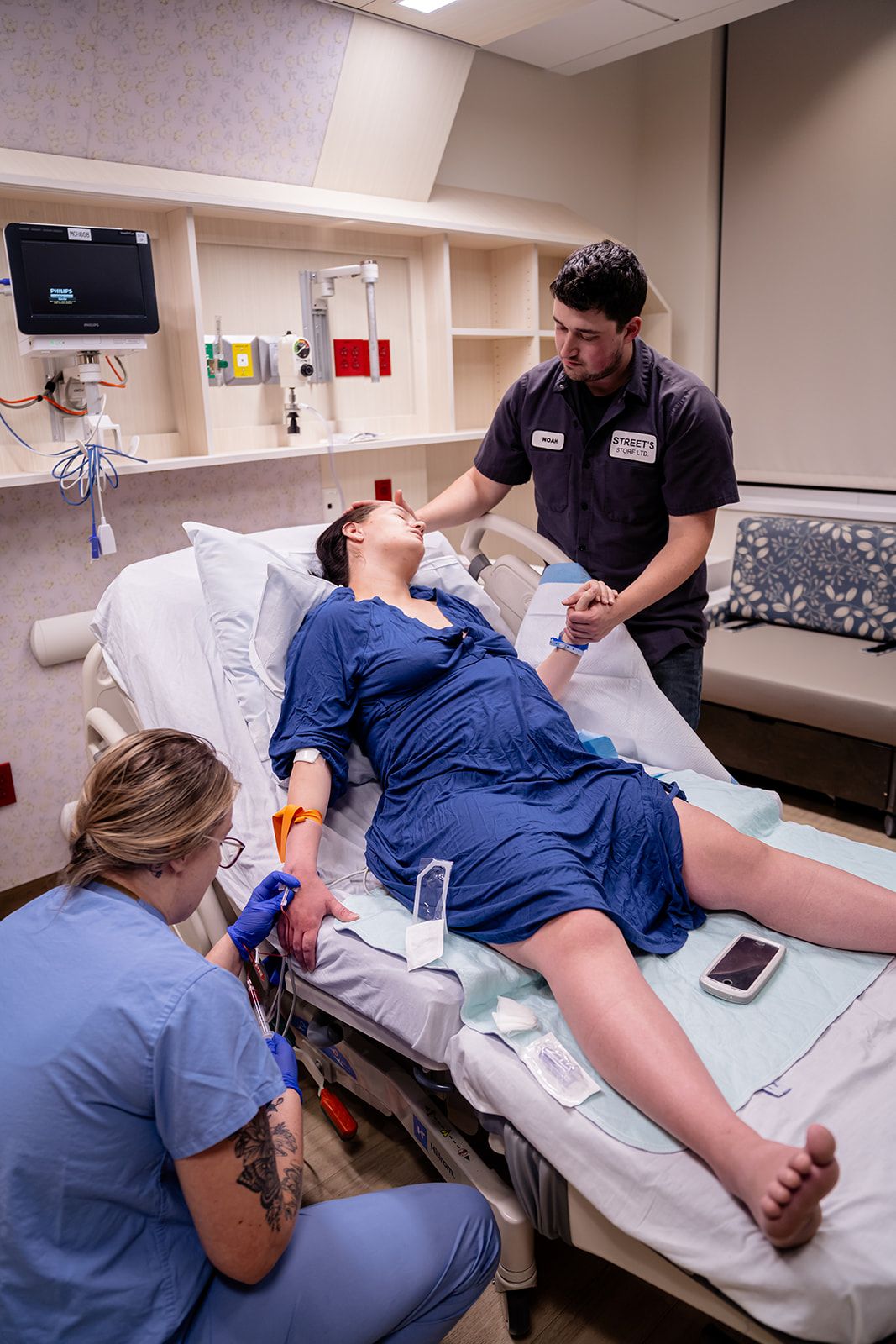 Medical team assisting pregnant woman in labor in hospital room while partner holds her hand supportively.