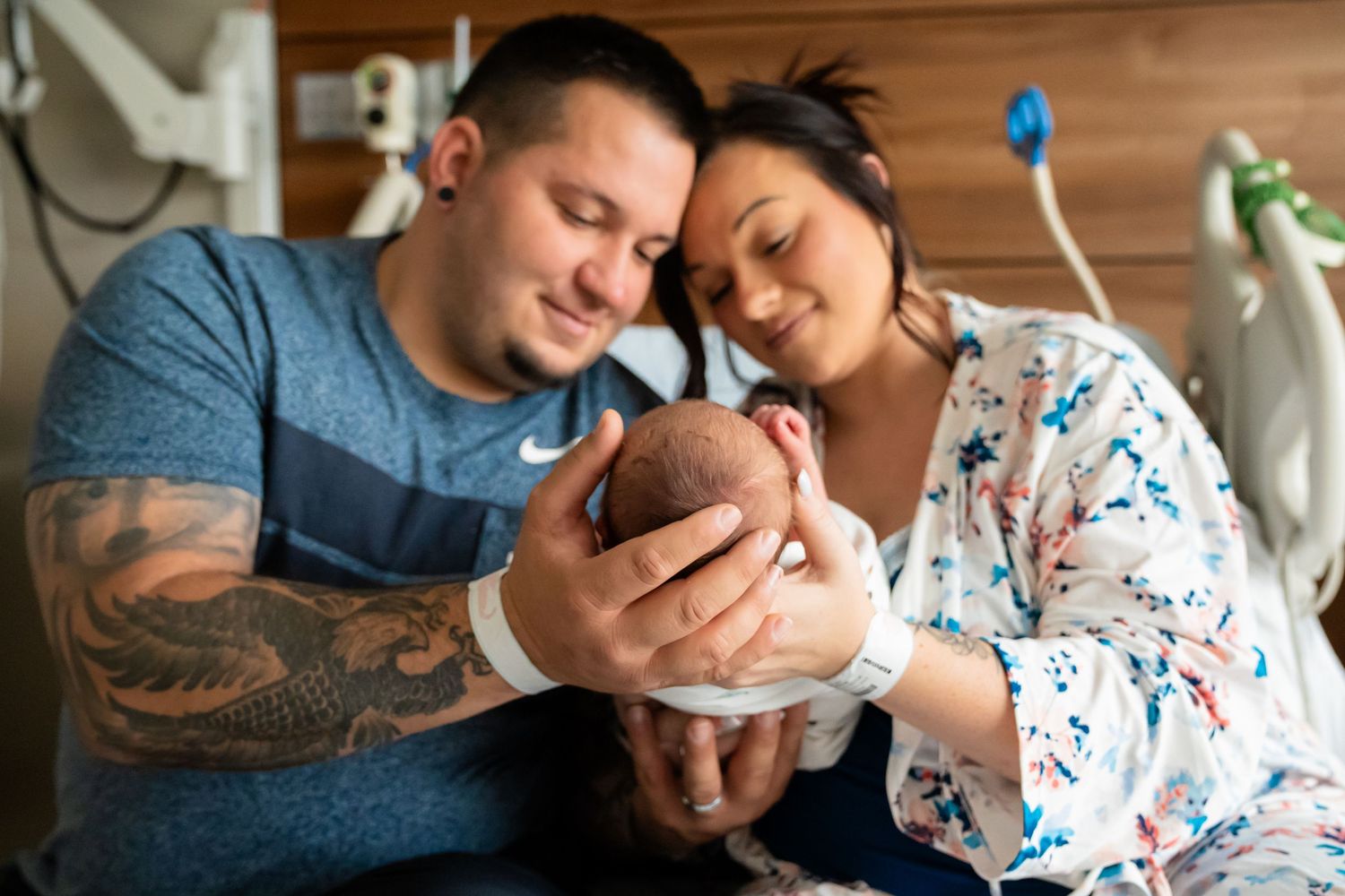 New parents lovingly cradle their newborn baby in a hospital room, smiling with joy after birth.