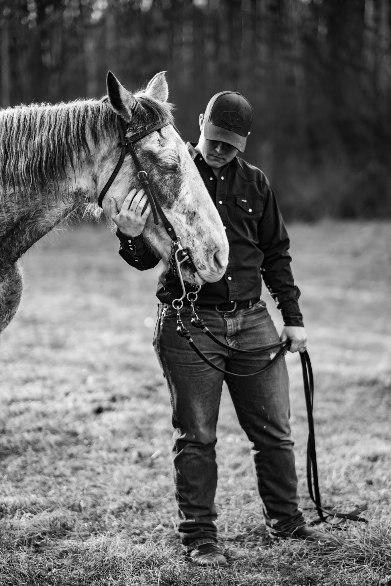 Black and white photo of a person bonding with a horse in an open field.