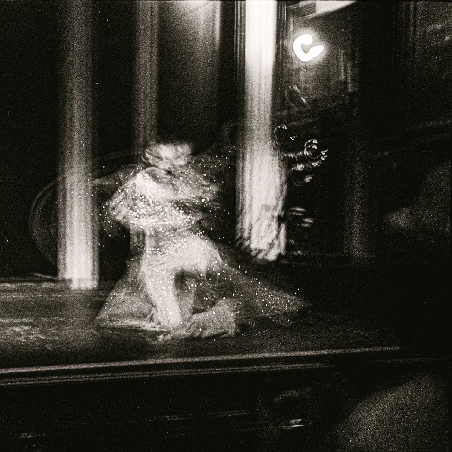 Ethereal black and white long exposure photograph of a dancer performing in a dimly lit venue.