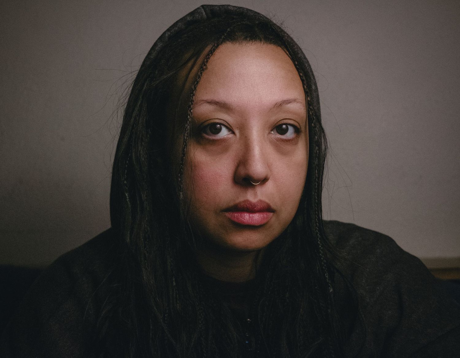 Close-up portrait of a young woman with dark hair and natural makeup against a neutral background.