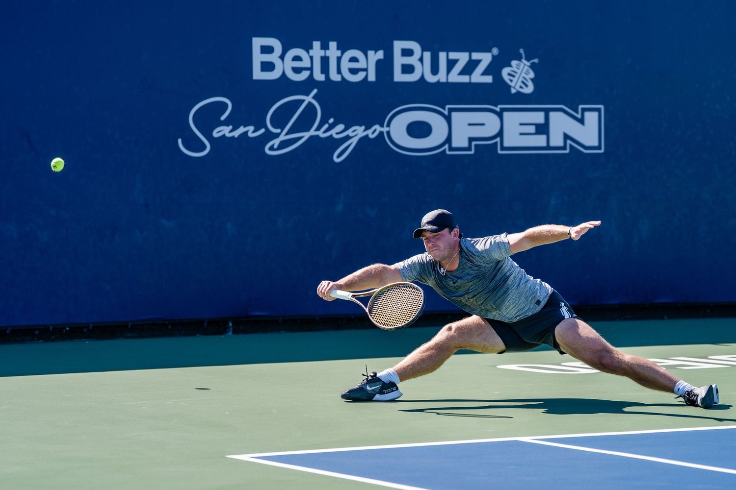 Tennis player lunges wide to return a shot at the Better Buzz San Diego Open.