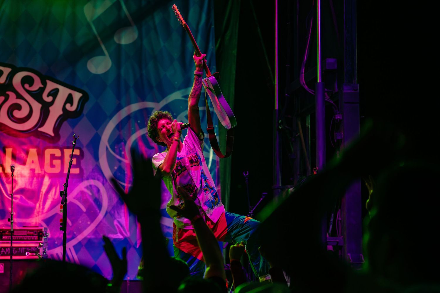 Rock guitarist leans back dramatically under vibrant purple and pink stage lights at Surfest.