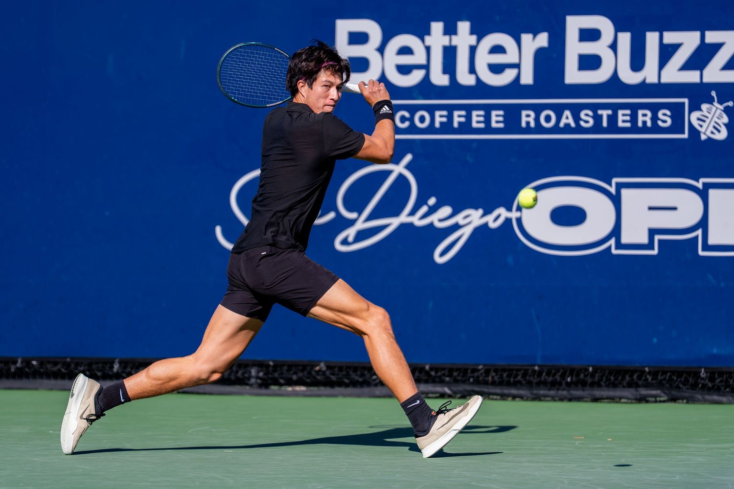 Tennis player stretches for a powerful backhand return at the Better Buzz Coffee Roasters San Diego Open.
