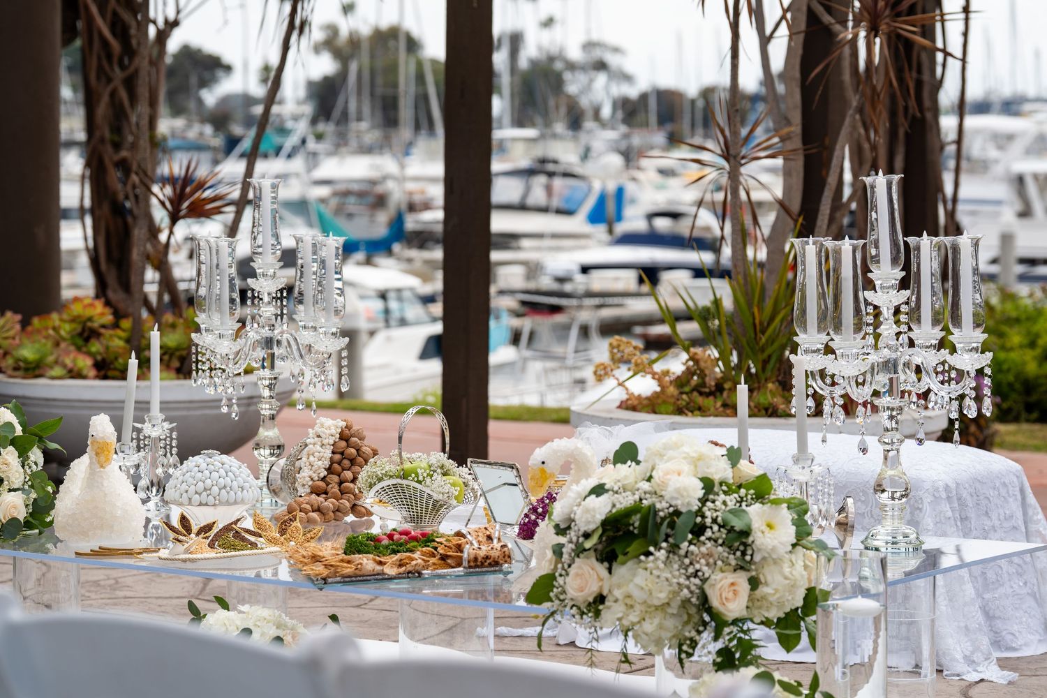 Elegant wedding reception table with crystal candelabras, white floral arrangements, and a marina backdrop.
