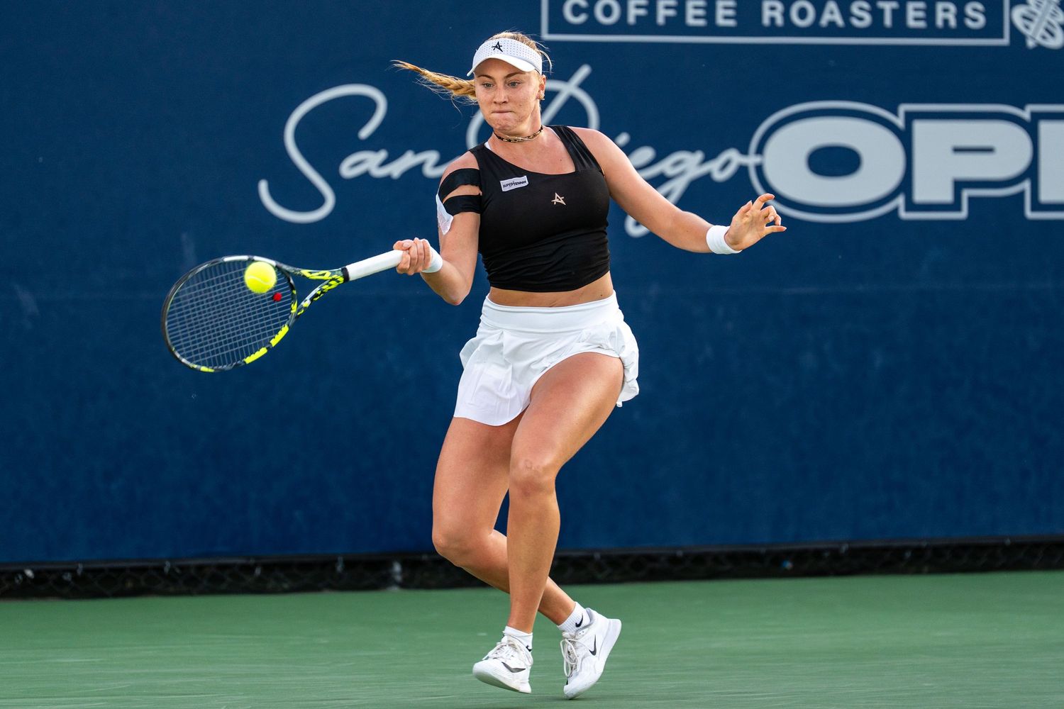 Female tennis player hits forehand at San Diego Open Coffee Roasters tournament.
