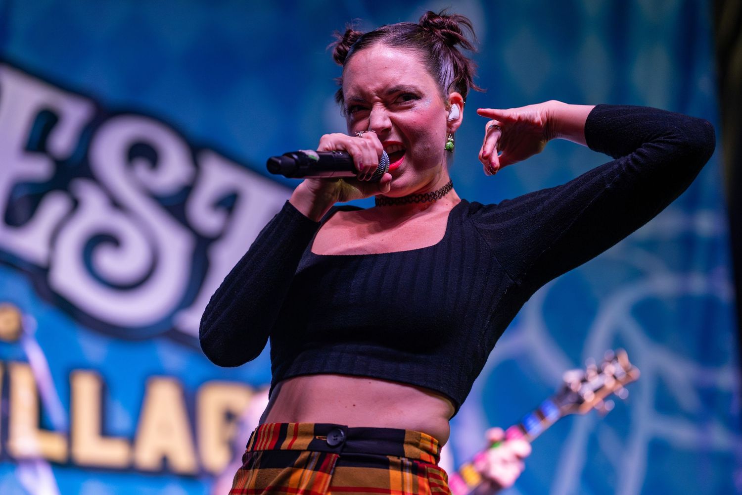 Female singer performs passionately on outdoor stage at Surfest Village music festival.
