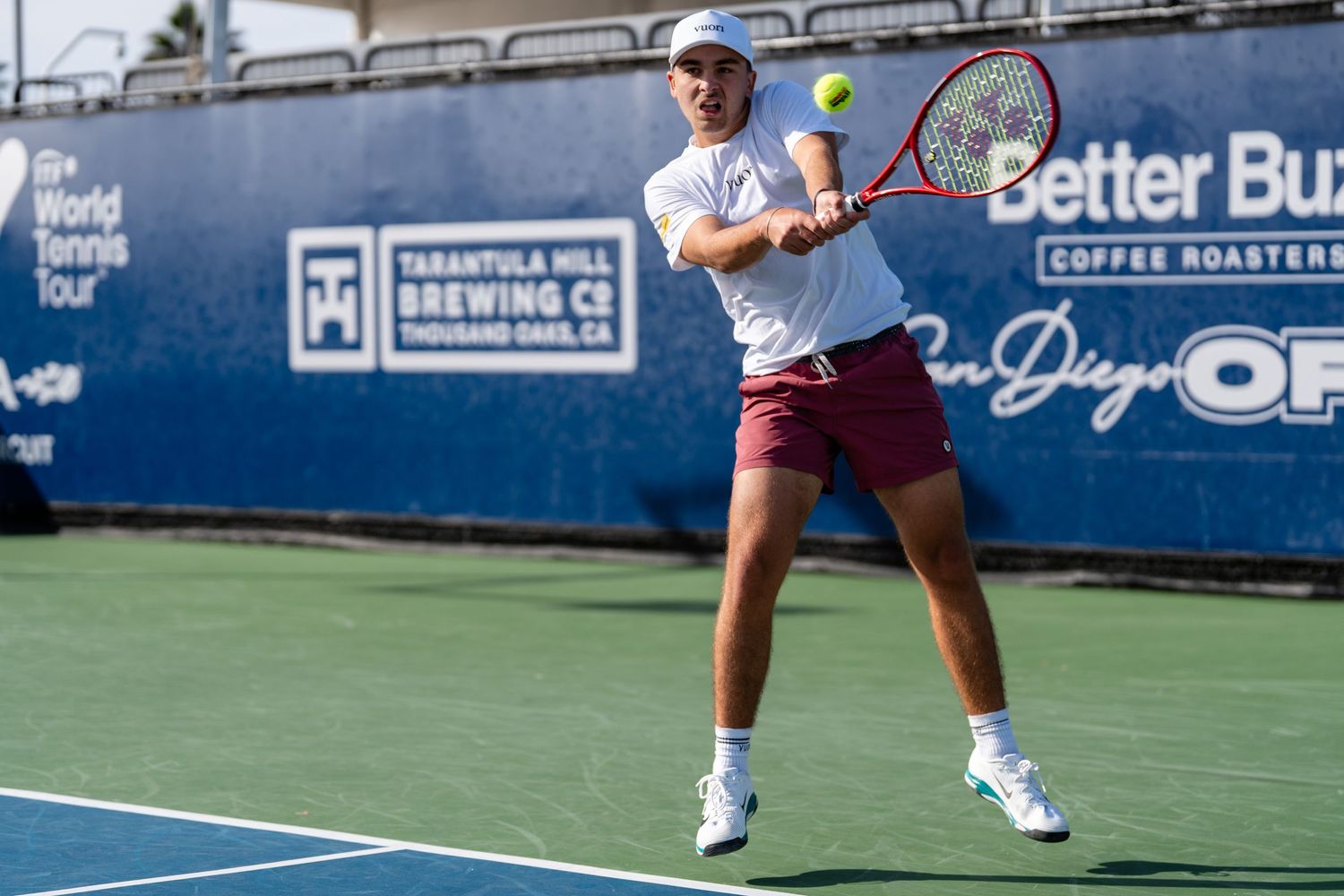 Male tennis player hits powerful backhand shot at Better Buzz San Diego Open tournament.