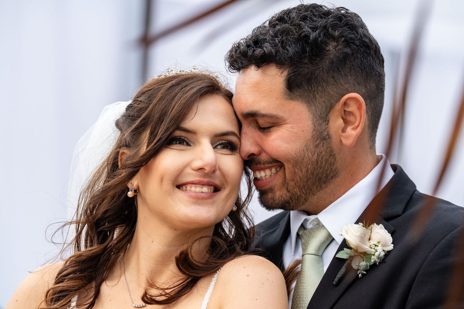 Happy bride and groom share a romantic moment, smiling closely together on their wedding day.
