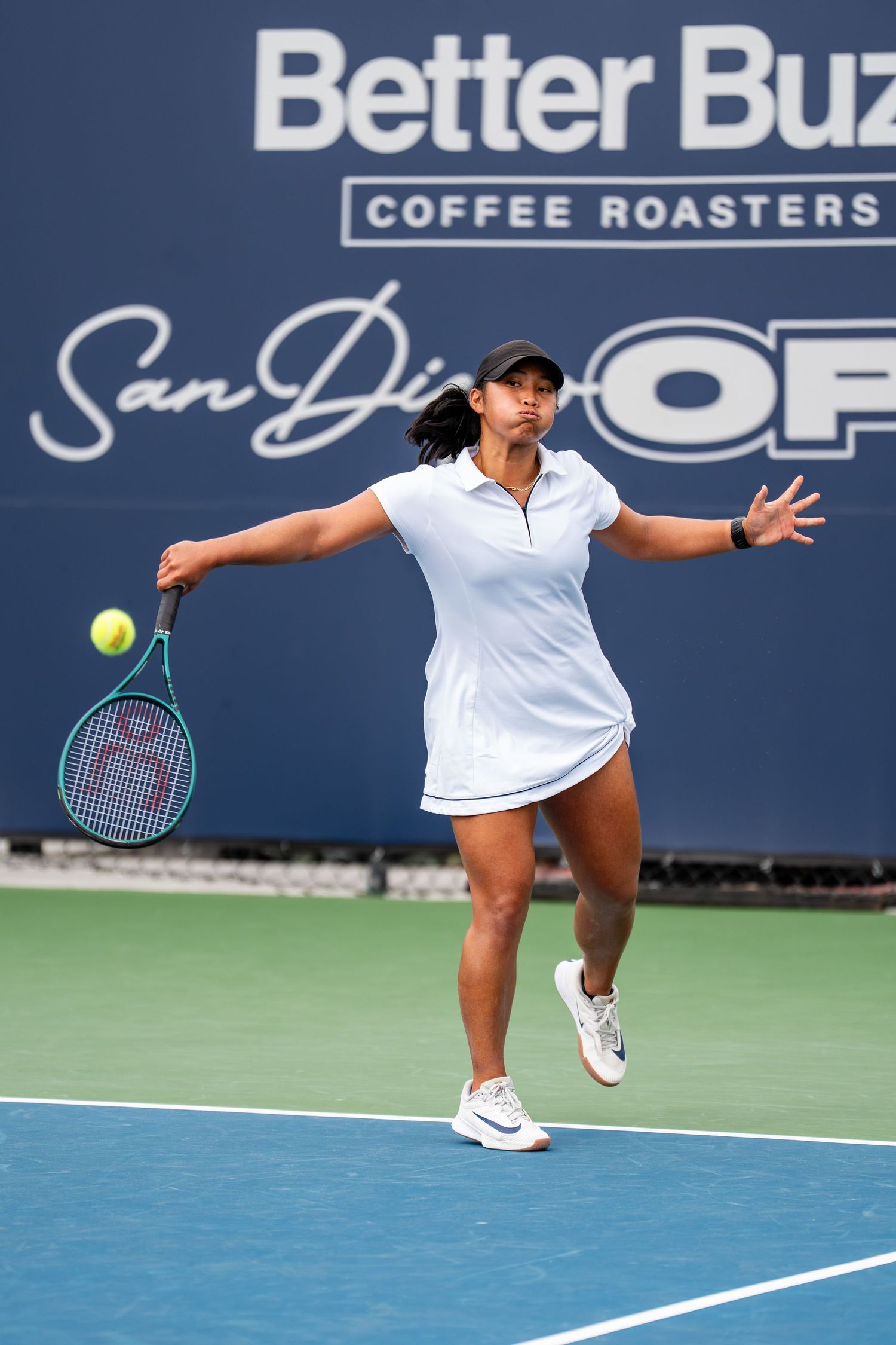 Female tennis player in white hits forehand at Better Buzz Coffee Roasters San Diego Open.