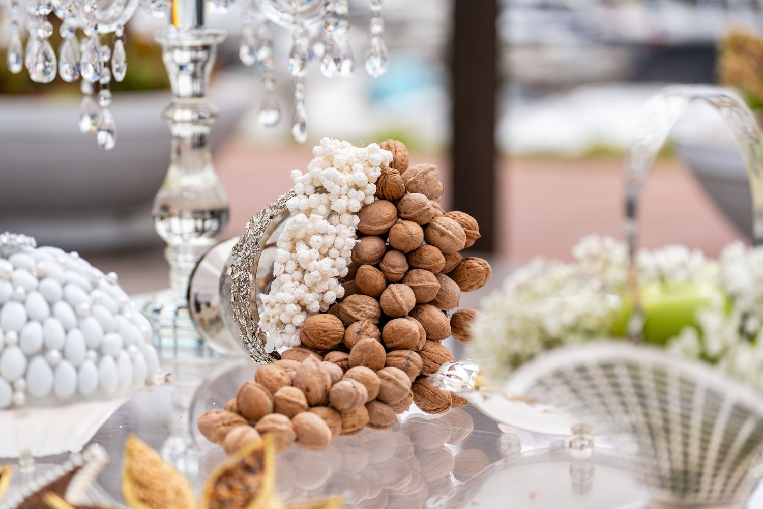 Elegant display of walnuts and white sugar-coated almonds in a crystal bowl at a wedding candy buffet.