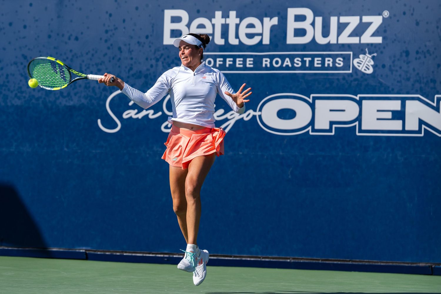 Female tennis player leaps to hit forehand at Better Buzz San Diego Open tournament.