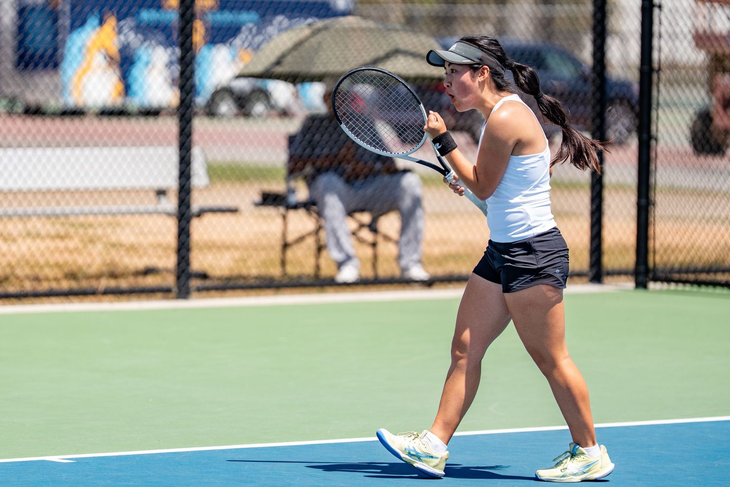 Young female tennis player prepares to hit a backhand shot during an outdoor tennis match.