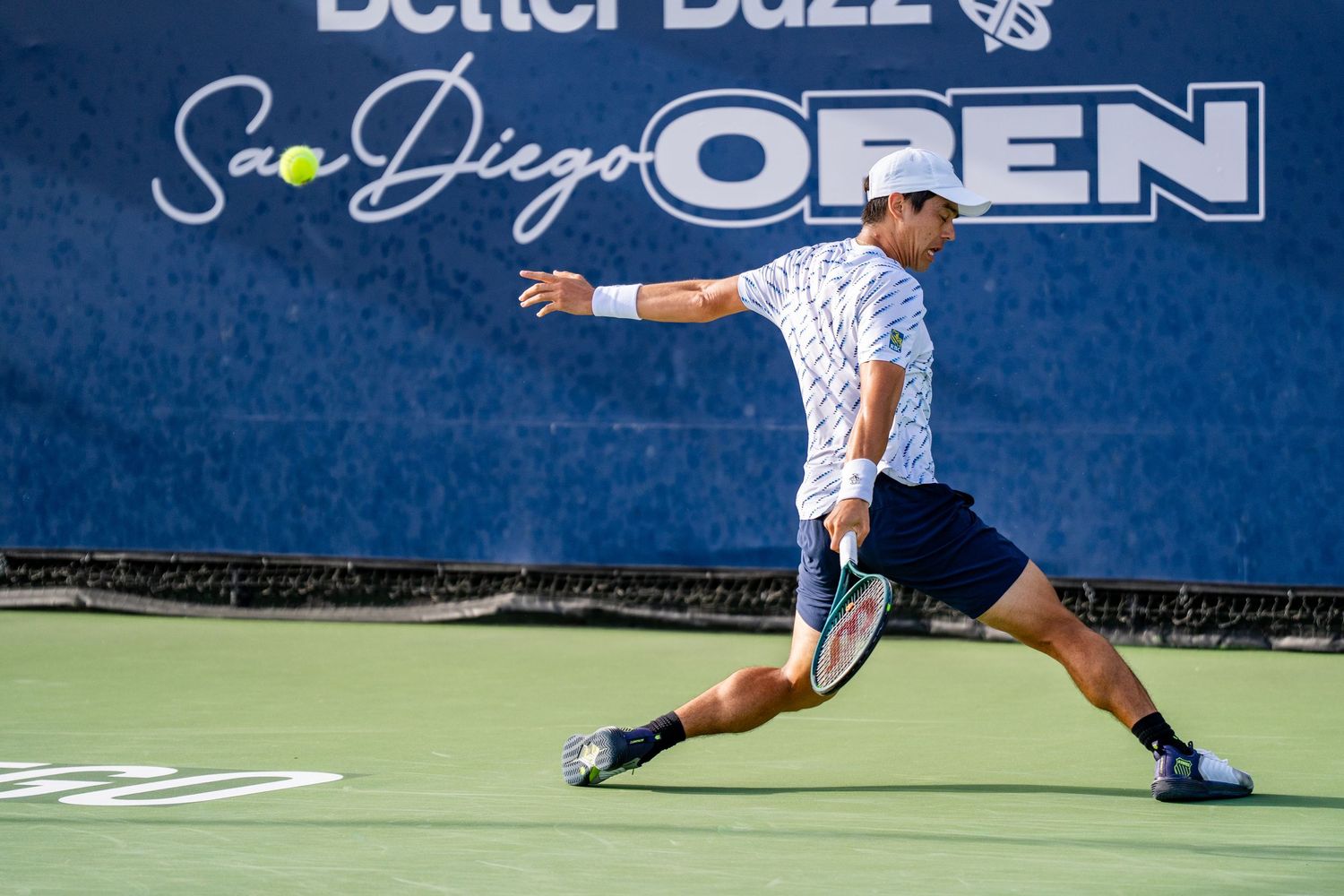 Tennis player lunges for a forehand shot at the Better Ball San Diego Open tournament on a sunny day.