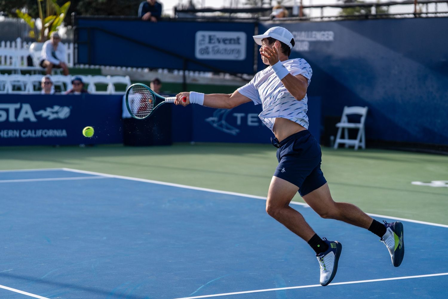 Professional tennis player leaps to hit a forehand shot during an outdoor hard court tournament match.